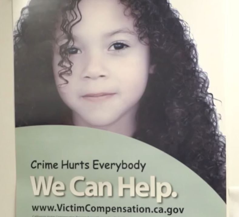 A flyer featuring a young girl with curly hair and a calm expression. The text on the flyer reads: 'Crime Hurts Everybody. We Can Help.' Below the message is a web address: www.VictimCompensation.ca.gov